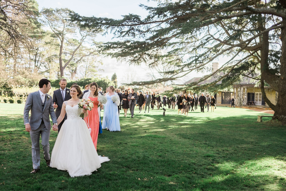 Alice & Rob's guests follow them in a procession across the lawn. Photo: James Day